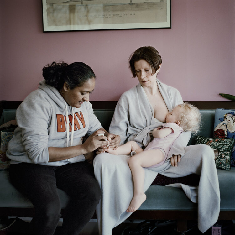 A woman feeds her baby while her nails are being done.