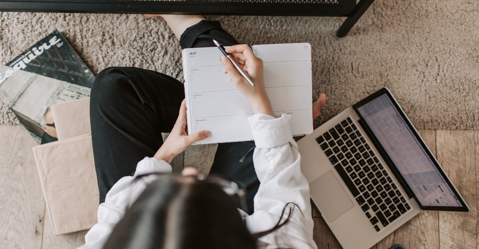 A woman sitting in front of her computer and notebook.