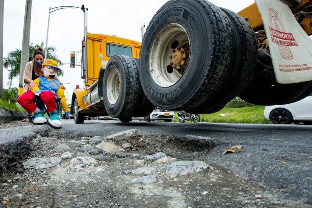 Journalist holding a dummy on a Medellin (Colombia) road in need of repair.